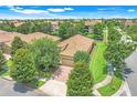 Aerial view of a single-story home boasting a tile roof, manicured lawn, and a brick-paved driveway in a lush community at 1300 Island Green St, Davenport, FL 33896