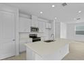 Bright kitchen with white cabinets, stainless steel appliances, quartz countertops, and an island with a sink at 227 Bull Frog Ln, Umatilla, FL 32784