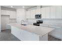 Bright kitchen featuring white cabinetry, stainless steel appliances, a spacious island and gray tile floors at 232 Flag Lilly Ln, Umatilla, FL 32784