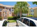Condo building exterior with brick accents, lush landscaping, and a glimpse of a neighboring yellow building at 2438 Sweetwater Club Cir # 50, Kissimmee, FL 34746