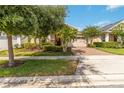 Charming single-story home with a well-manicured lawn and a brick-paved driveway and mature landscaping at 5009 E Fountainwood Dr, St Cloud, FL 34772