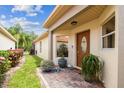 Inviting front entrance with a decorative wooden door, brick pathway, and lush potted plants at 608 Grand Canal Dr, Poinciana, FL 34759