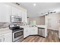 Bright kitchen with stainless steel appliances, white cabinets, and wood-look flooring at 7013 Beargrass Rd, Harmony, FL 34773
