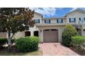 Charming townhouse featuring a red brick driveway, an attached garage, and mature landscaping at 13885 Arclid St, Orlando, FL 32832