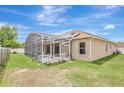 An inviting screened-in lanai attached to a stucco home with solar panels and a spacious backyard at 143 Brixham Ct, Kissimmee, FL 34758