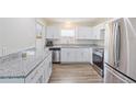 Stylish kitchen featuring stainless steel appliances, white cabinets, granite countertops, and modern flooring at 1712 Melvin Ave, Orlando, FL 32806