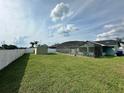 Large, green backyard featuring a screened-in pool area and storage shed near a white fence at 2410 Sweetwater Blvd, St Cloud, FL 34772