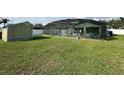 Screened-in pool with patio furniture, surrounded by a well-maintained green lawn and storage shed at 2410 Sweetwater Blvd, St Cloud, FL 34772