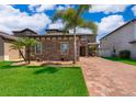 Charming single-Gathering home with brick accents, a manicured lawn, and a brick paver driveway at 3159 Somerset Park Dr, Orlando, FL 32824