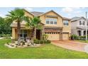 Charming tan two-story home featuring a brick-paved driveway, manicured lawn, and a spacious three-car garage at 3899 Mount Vernon Way, Kissimmee, FL 34741
