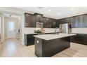 Modern kitchen featuring dark cabinets, stainless steel appliances, and a center island with a quartz countertop at 8042 Glenlloyd Ave, Winter Garden, FL 34787