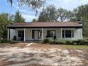 Exterior view of a charming single story home with columns, covered front porch, stone path, mature trees, and spacious front yard at 8310 Happy Trails, Kissimmee, FL 34747