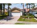 Two-car garage with brick driveway, lush lawn, attractive landscaping, and solar panels on the roof at 12041 Kajetan Ln, Orlando, FL 32827
