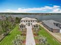An aerial view of this luxurious home with manicured lawn overlooking a serene lake, embodying waterfront elegance at 15121 Pendio Dr, Montverde, FL 34756
