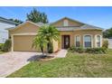 Charming single-story home featuring a well-manicured lawn, brick driveway, and a beautiful palm tree in the front yard at 15341 Groose Point Ln, Clermont, FL 34714