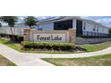 The Forest Lake community sign is framed by colorful flowers, landscaping, and sidewalks at 1556 Aspen Ave, Davenport, FL 33837