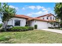 Charming single-story home showcasing a red tile roof, well-maintained lawn, and an attached two-car garage at 16614 Lazy Breeze Loop, Clermont, FL 34714