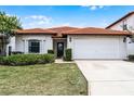 Charming single-story home showcasing a red tile roof, well-maintained lawn, and an attached two-car garage at 16614 Lazy Breeze Loop, Clermont, FL 34714