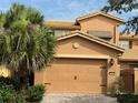 Two car garage with brick paved driveway and mature landscaping including a palm tree at 2495 Palm Tree Dr, Kissimmee, FL 34759