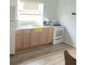 Bright kitchen featuring white appliances, wood-look floors, and light wood cabinets at 380 S Echo Dr, Lake Alfred, FL 33850
