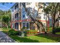 A tan two-story condo building featuring white trim, screened balconies, and lush green landscaping at 6214 Stevenson Dr # 106, Orlando, FL 32835