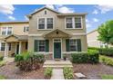 Charming two-story townhome boasts lush landscaping and a welcoming green front door with a wreath at 7144 Five Oaks Dr, Harmony, FL 34773