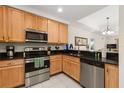 Bright kitchen with stainless steel appliances, wooden cabinets, and granite countertops, with eat in bar at 9055 Treasure Trove Ln # 409, Kissimmee, FL 34747