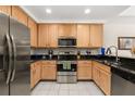 Well-lit kitchen featuring stainless steel appliances, wood cabinets, and dark countertops with tile floor at 9055 Treasure Trove Ln # 409, Kissimmee, FL 34747