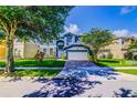 Charming two-story blue home with landscaped front yard and a brick paver driveway at 12715 Moss Park Ridge Dr, Orlando, FL 32832
