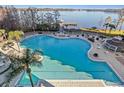 Expansive outdoor pool with ample lounge seating, lush landscaping, and a picturesque lakeside view at 13415 Blue Heron Beach Dr # 401, Orlando, FL 32821