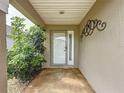 Cozy front porch featuring a white door with sidelight, decorative metal art and mature landscaping at 1428 Park Pl, Haines City, FL 33844