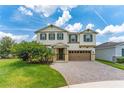 Two-story home with a brick paved driveway, two-car garage, green shutters, and manicured landscaping at 14421 Ward Rd, Orlando, FL 32824