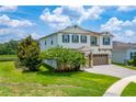 Two-story home with a two-car garage, green shutters, mature trees, and a brick paved driveway at 14421 Ward Rd, Orlando, FL 32824