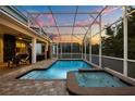 Inviting screened-in pool and spa with poolside seating and lush vertical garden accents at 1560 Maidstone Ct, Davenport, FL 33896