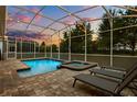 Relaxing screened-in pool and spa area with brick pavers and string lights, perfect for entertaining at 1560 Maidstone Ct, Davenport, FL 33896