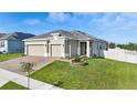 Well-maintained home featuring a three car garage, brick driveway, and verdant, landscaped front yard at 168 Jensen Dr, Groveland, FL 34736
