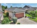 Well-maintained home with a two-car garage, brick-paved driveway, lush landscaping, and architectural details at 328 Toldedo Rd, Davenport, FL 33837