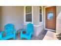 Inviting front porch with tiled flooring, two bright blue Adirondack chairs, and a stylish glass-paneled front door at 328 Toldedo Rd, Davenport, FL 33837