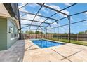 Inviting screened-in pool area with travertine tile decking and a view of the fenced backyard at 3824 Hickory Tree Rd, St Cloud, FL 34772