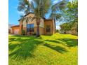 Lawn view of a two-story tan home with a palm tree and manicured grass at 4720 Doral Pointe Dr, Kissimmee, FL 34758