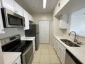 Well-equipped kitchen with stainless steel appliances, white cabinets, and neutral countertop and tile flooring at 1020 Siena Park W Blvd # 304, Kissimmee, FL 34747