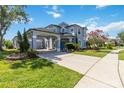Elegant two-story home featuring a porte-cochere, lush landscaping, and classic architectural details at 12134 Shadowbrook Ln, Orlando, FL 32828