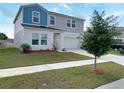 A two-story home with blue and gray siding, a manicured lawn, and a two-car garage at 1404 Axel Cir, Winter Haven, FL 33880
