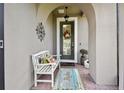 Inviting covered front porch with a cozy bench, decorative wreath, and decorative wall art at 1703 Encinitas Way, Kissimmee, FL 34759