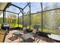 Relaxing screened patio with lounge chairs, brick flooring, and a view of the surrounding greenery at 1703 Encinitas Way, Kissimmee, FL 34759
