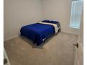 Cozy bedroom with carpet floors, a window, and a comfortable bed with blue bedding at 200 Citrine Loop, Kissimmee, FL 34758