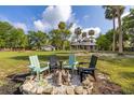 Spacious yard featuring a fire pit with Adirondack chairs with lush green grass and mature trees at 525 W Blue Springs Ave, Orange City, FL 32763
