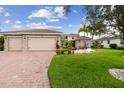 Charming single-story home featuring a brick driveway, three-car garage, and meticulously maintained lawn at 561 Tapatio Ln, Kissimmee, FL 34759