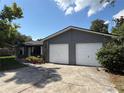 View of gray home featuring a two-car garage, complemented by a lush yard and inviting landscaping at 6489 Creation St, St Cloud, FL 34771