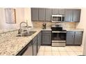 Well-lit kitchen with gray cabinets, granite countertops, stainless steel appliances, and tiled flooring at 8517 Bay Lilly Loop, Kissimmee, FL 34747